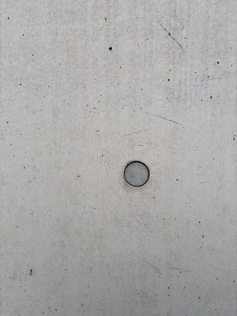 Photograph of concrete wall with circular cut out, rough surface